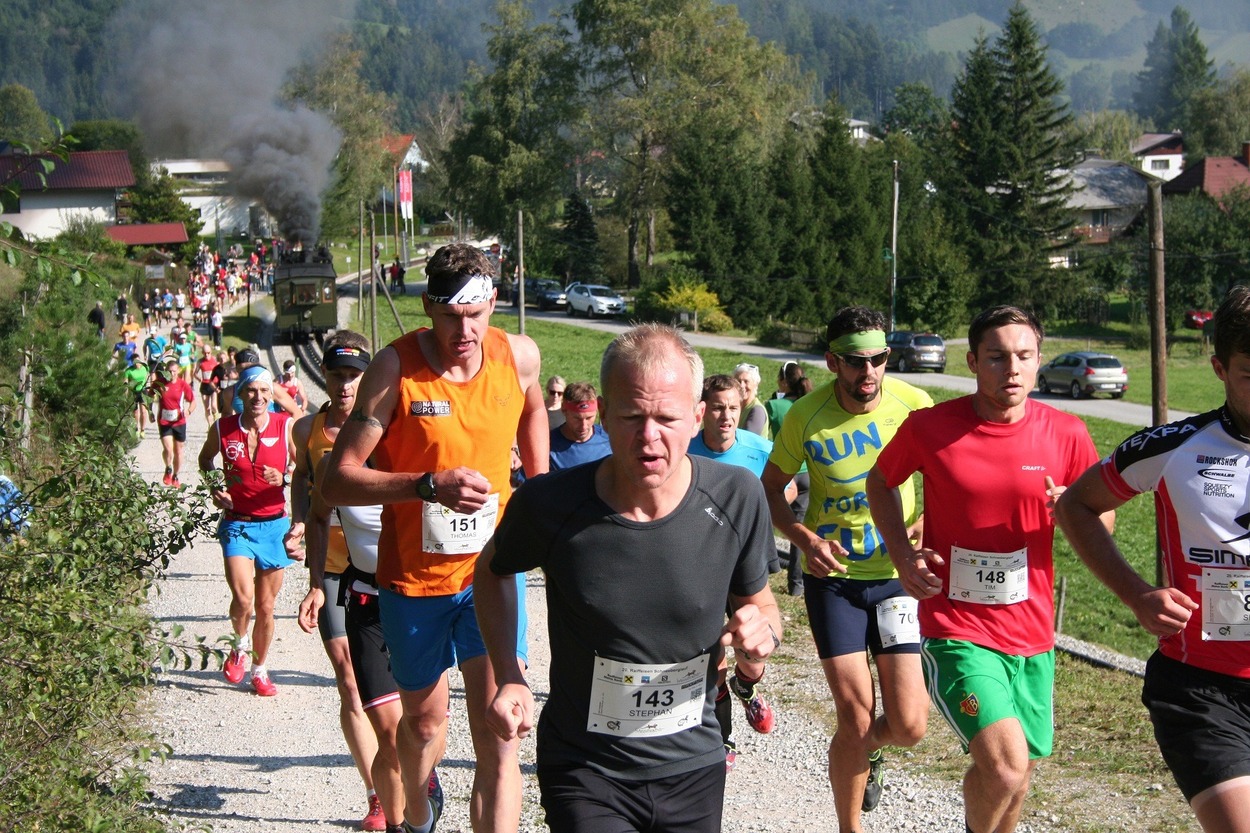 Sportlerinnen und Sportler nach dem Start des Schneeberglaufs begleitet von der Dampflok